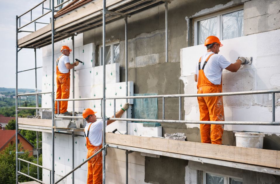 Homlokzati hőszigetelés épület homlokzatán, szigetelő panelek és vakolat alkalmazása az energiahatékonyság növelésére.